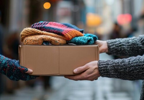 2-closeup-hands-passing-donation-box-filled-with-clothing-essentials-charity-worker-urban-setting_1295806-43252